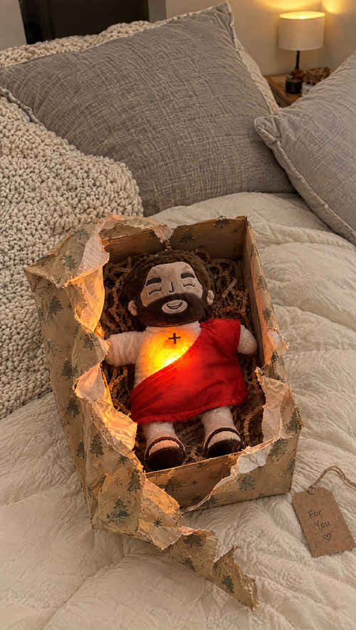 Glowing Jesus plush in a gift box with Christmas wrapping paper